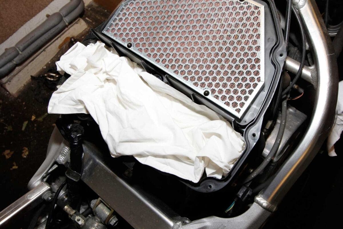 2: Unscrew the top of the air box, and you’ll find the filter. Lay a clean piece of rag over the carb inlets to stop anything dropping down there.