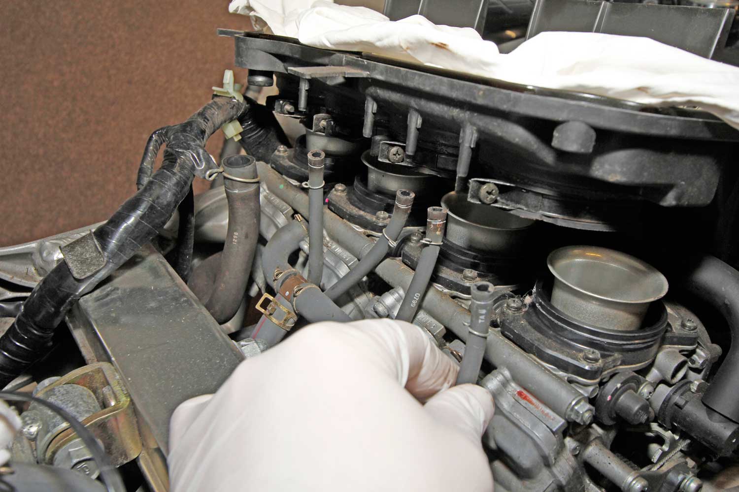 4: Theoretically, the plugs can be changed from behind the radiator, but I find it a lot easier to go in from the top. The four clamps that attach the air box lower to the carbs need loosening, and the vacuum pipes have to come off their blank plugs.