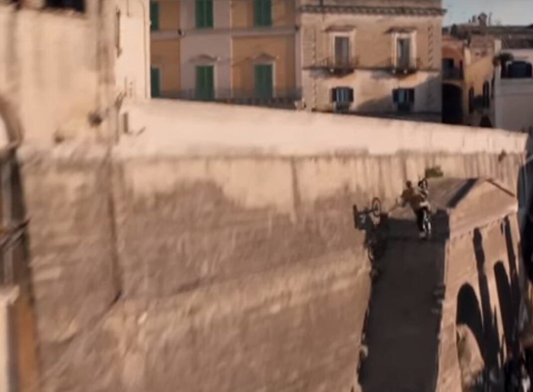 Side of an old wall - check. Motocross bike - check. Stuntman with a camera helicopter chasing him - check. Right people, let's get this done. Nice and high please, chap...