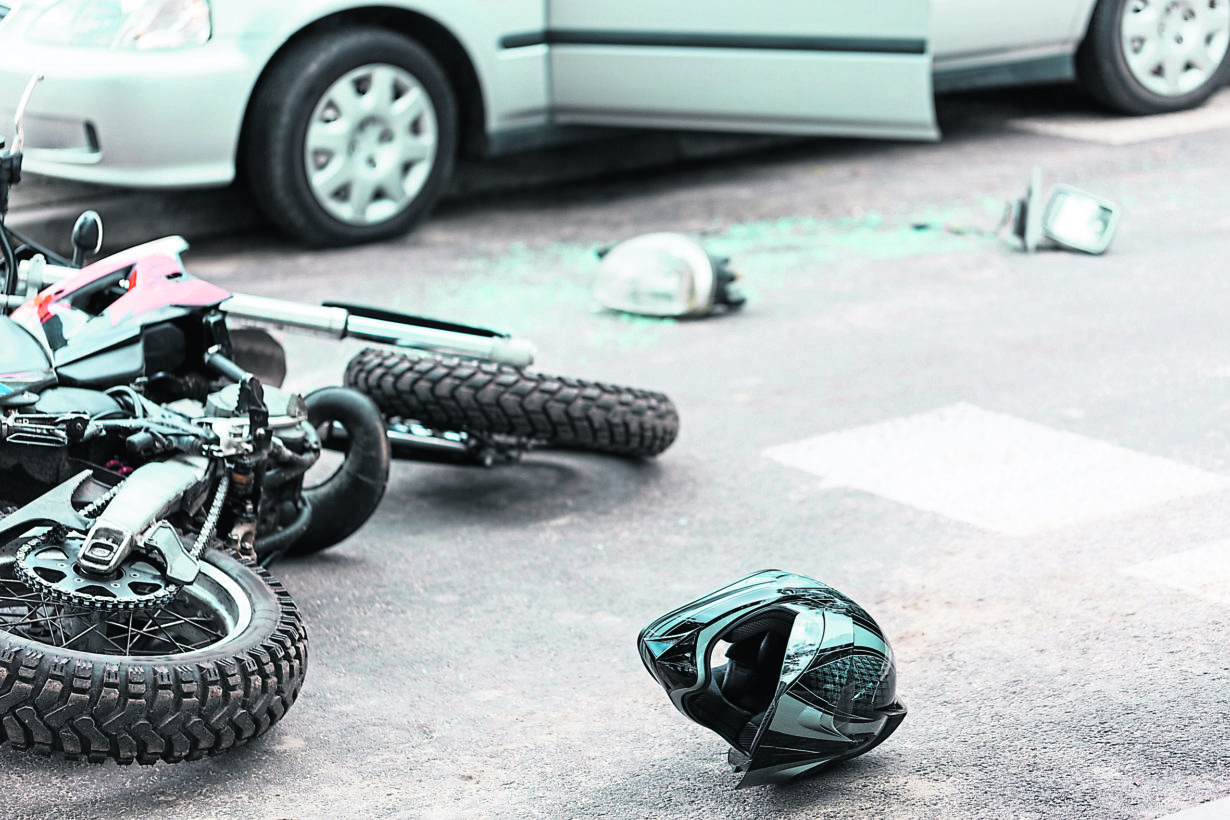 Overturned motorcycle and helmet on the street after collision with the car